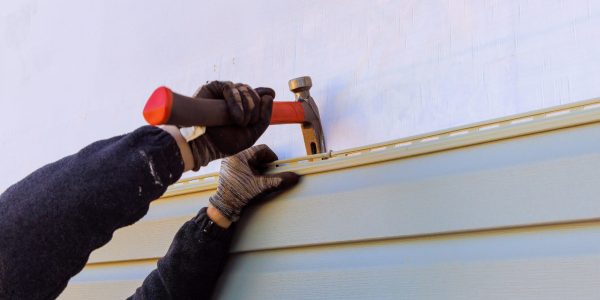 Damaged plastic siding of house is replaced during reconstruction of its exterior